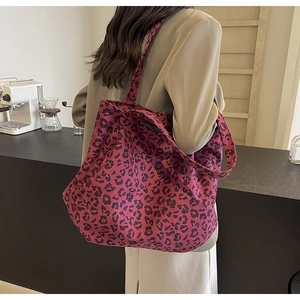 Vue détaillée du grand sac cabas en toile rose à motif léopard porté avec un tailleur