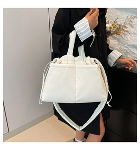 On-body view of a white quilted shoulder bag featuring soft nylon fabric and drawstring detail
