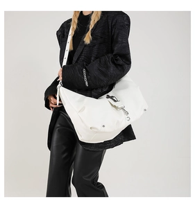 Détail d'un sac à bandoulière en similicuir blanc avec boucle croisée et rivets