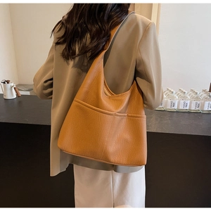Macro shot of large caramel PU leather shoulder bag with textured stitching and pockets