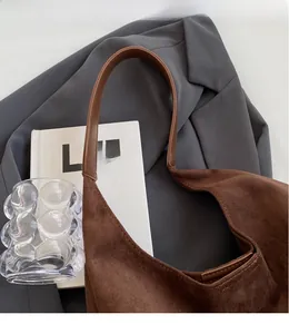 Close-up of brown suede hobo bag with long strap against a stylish lifestyle backdrop