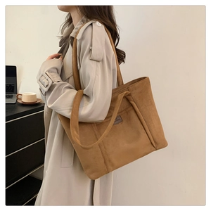 Detail view of the soft brown suede tote bag with a small rectangular logo patch on front