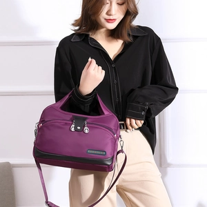 Détail du sac bandoulière en nylon violet avec plusieurs zips et plaque de mode