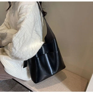 Detail of black faux leather tote bag with wide strap and large exterior pocket