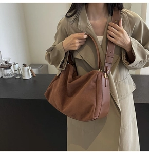 Close-up of brown suede baguette bag with smooth leather strap detail on a stylish model