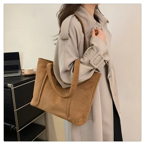 Detail of caramel suede tote bag shown in a professional office setting with a laptop