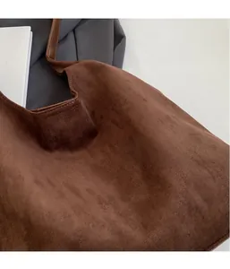 Close-up of dark brown suede tote bag showing soft matte texture and precise stitching