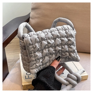 Detail der grau gesteppten Puffy-Schultertasche mit glattem Satin-Finish und Knotendesign