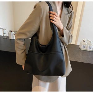 Detail of a black pebbled leather hobo tote bag featuring a functional front pocket and wide strap