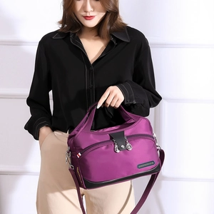 Vue détaillée du sac à bandoulière en nylon magenta avec étiquette mode et zips argentés