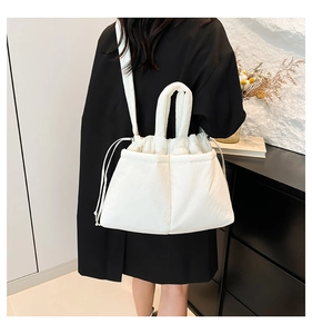 Detail view of a white quilted drawstring shoulder bag with a soft puffy nylon texture
