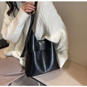 Detail of black faux leather tote bag with functional front pockets and glossy texture