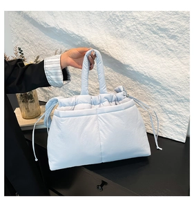 Close-up of quilted ice blue puffer tote bag featuring soft handles and drawstring detail
