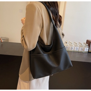 Close-up of black lychee-textured PU leather hobo bag with wide shoulder strap on model