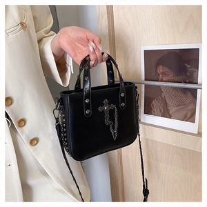 Close-up of black PU leather bag with silver cross, metal chains and punk style rivets