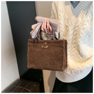 Detailed view of brown teddy plush tote bag with dark leather handles and gold buckle