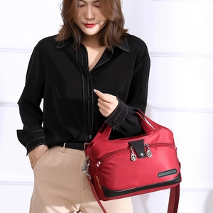 Détails d'un sac à main rouge en nylon imperméable avec logo fashion et sangles noires