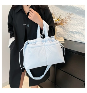 Detail of light blue quilted crossbody bag with drawstring closure and soft texture