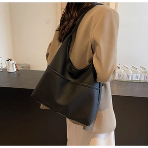 Detail view of a black PU leather tote bag with functional front pocket and smooth texture