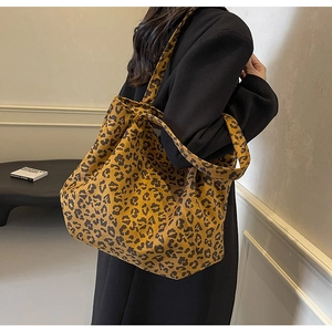 Détail du grand sac cabas en toile avec imprimé léopard jaune porté par un modèle