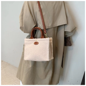 Detail showing the plush faux fur texture and brown leather strap of the crossbody bag