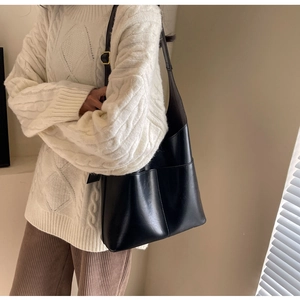 Chic black PU leather tote bag with gold buckle on casual white knit sweater outfit