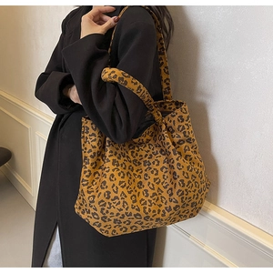 Gros plan du sac cabas en toile à motif léopard porté avec un manteau d'automne noir