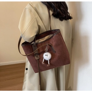 Detail of dark brown velvet tote bag with rhombus pattern and fuzzy doll charm