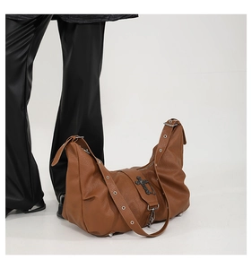 Détail du sac hobo marron avec croix argentée vintage et décoration de chaînes