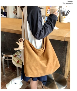 Brown suede crossbody bag with plush dog charm accessory in a cafe setting