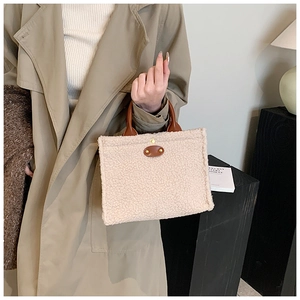 Detail of beige fleece tote bag featuring brown leather straps and smooth fuzzy texture