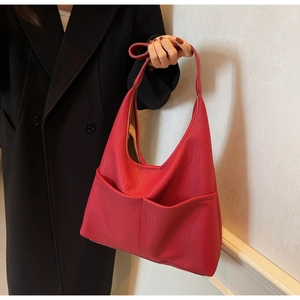 Detail of red pebbled PU leather hobo shoulder bag with double pockets on black coat
