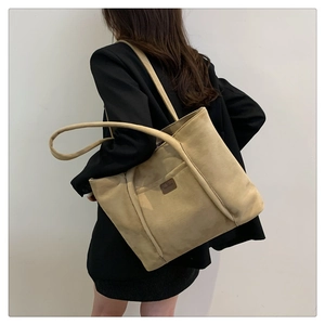 Detail of beige corduroy tote bag with texture focus and a small brand logo patch