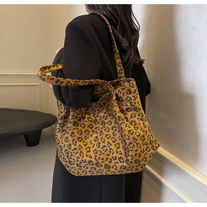 Vue latérale détaillée du sac cabas tendance en toile à imprimé léopard porté avec un costume noir