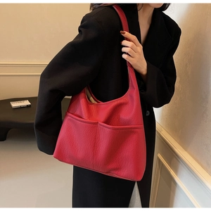 Detail view of a large red pebbled PU leather tote bag with functional front pockets