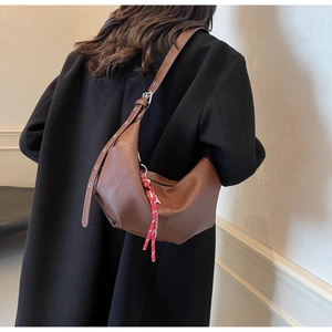 Detail of a brown PU leather half-moon crossbody bag with woven zipper puller