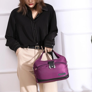 Détail d'un sac à main en nylon violet avec doubles fermetures éclair et plaque de mode