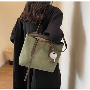 Detail of dark green velvet tote bag with quilted pattern and brown leather straps