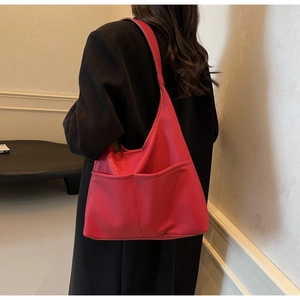 Detail view of the red lychee texture leather surface and front symmetrical pockets of the tote bag