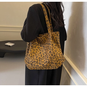 Sac fourre-tout en toile à imprimé léopard porté avec un long manteau noir élégant