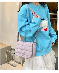 Detail view of light purple quilted crossbody bag with adjustable textile shoulder strap