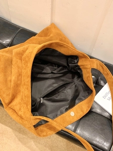 Detail view of tan suede tote bag featuring internal zip pocket and magnetic closure