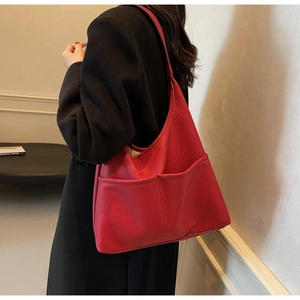 Detail of red oversized PU leather tote with front pockets styled on a black coat