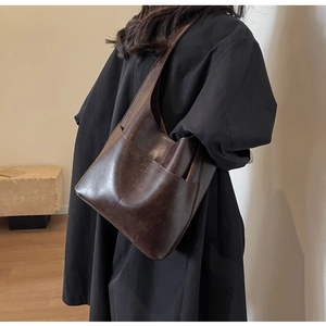 Close-up of a vintage dark brown oil-waxed leather shoulder bag with a large front pocket