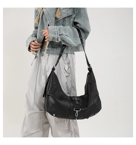 Détail du sac hobo noir avec pendentif croix gothique et rivets métalliques argentés