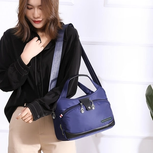 Sac bandoulière en tissu oxford bleu avec compartiments zippés et détails argentés