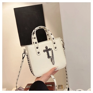 Close-up of white PU leather crossbody bag featuring metal studs and a large cross charm