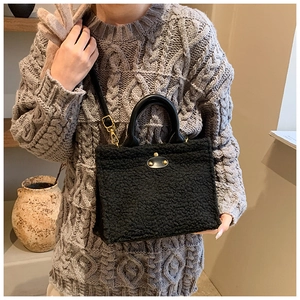Detail of black faux shearling tote bag featuring leather accents and gold twist lock