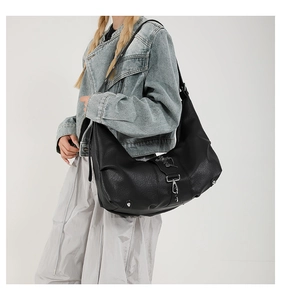 Détail du sac bandoulière noir en similicuir avec rivets argentés et pendentif croix