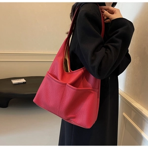 Detail of rose red textured leather hobo bag with front pockets on female model